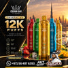 Promotional graphic for Crown Bar Crystal V2 disposable vape devices. Five devices in red, green, gold, and blue are displayed on a reflective surface with strawberries, ice, and a desert city skyline background.
