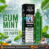 Crown Bar Al Fakher Crystal V2 Gum Mint 12K disposable vape and its packaging box, set against a dynamic background of ice cubes, water droplets, and fresh mint leaves. The product is green with a translucent cap, and the box is black with white and red text.