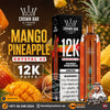 Crown Bar Al Fakher Crystal V2 Mango Pineapple disposable vape and its packaging box, set against a dynamic background of sliced mangoes, pineapples, and golden liquid splashes. The ad includes promotional text, a customer phone number, and a Tereilqos Store logo.